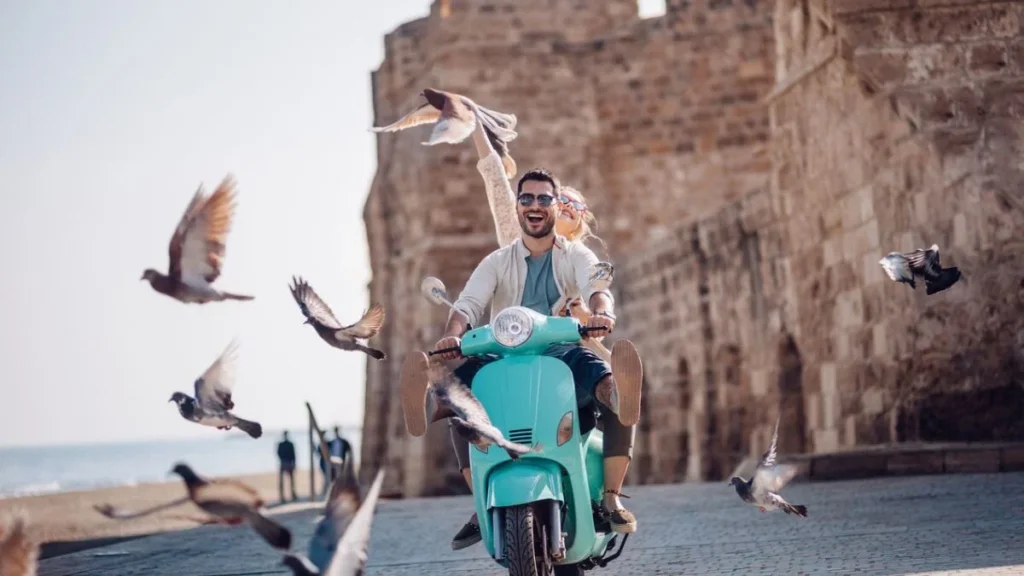 Pareja joven conectada a internet con su smartphone mientras pasean en scooter por Italia.