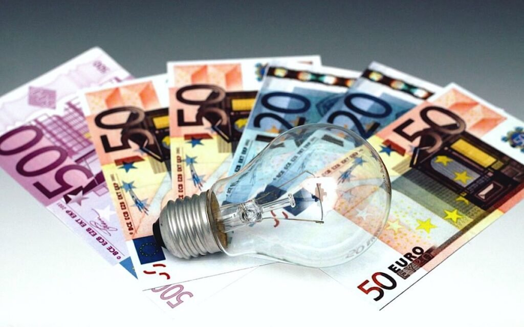 Bombilla sobre billetes de euros para ilustrar el artículo sobre cómo interpretar las facturas de luz y gas.