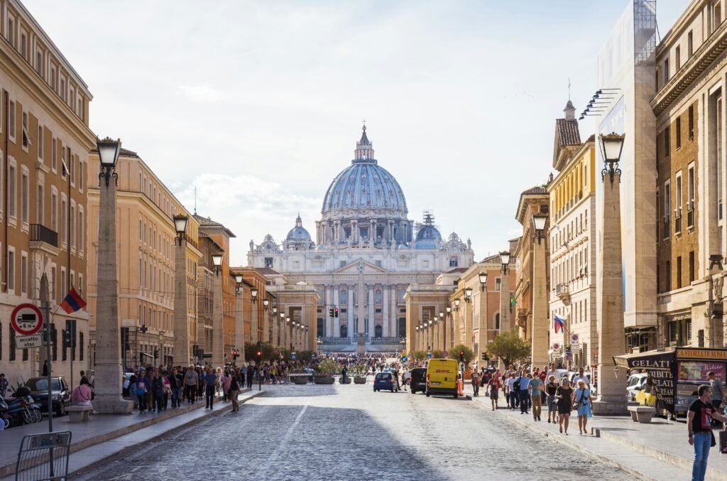 nulla osta ricongiungimento roma: Vista de la avenida hacia la Basílica de San Pedro con personas transitando.